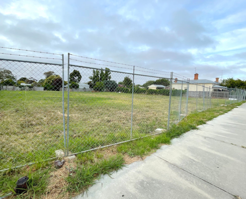 Description: Photo of a vacant residential block with temporary fence erected at the footpath. AS Planning are Town Planners in Victoria.